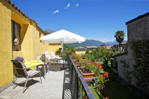 uma varanda com uma mesa e cadeiras e um guarda-sol em Casa Bel Giardino em Cannobio