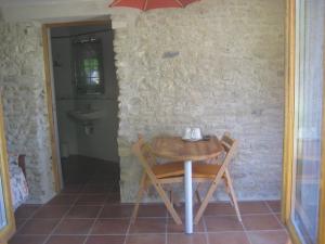 un tavolino e sedie in una stanza con parete di Chambre d'hôte Au col de Cygne a Blanzac-lès-Matha