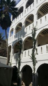 Jamala Guesthouse في لامو: مبنى ابيض امامه نخله