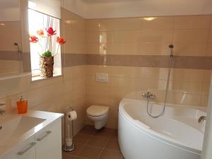 a bathroom with a tub and a toilet and a sink at Apartment Casa Eni in Dražice