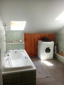 a bathroom with a tub and a washing machine at Chalet Lou Bella Vista in Auron