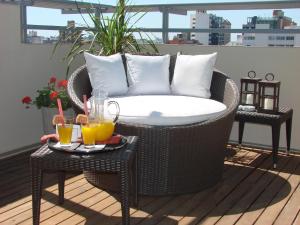 a wicker chair on a balcony with two tables with drinks at Zoom Apartments Hotel in Córdoba