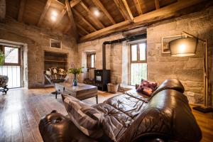 uma sala de estar com um sofá de couro e uma mesa em Aldea Rural Pazos De Arenteiro em Pazos de Arenteiro