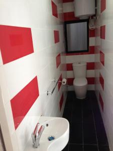 baño rojo y blanco con lavabo y aseo en Joe Ann Apartments, en San Julián