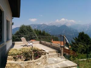 a chair sitting on a balcony with a view of mountains at Casa Pierini in Civenna