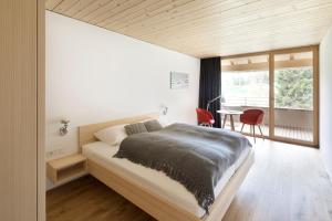 a bedroom with a bed and a large window at Hotel Tannahof in Au im Bregenzerwald