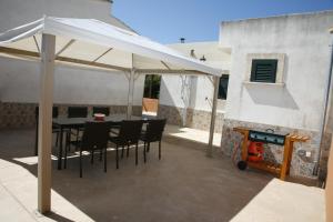einen weißen Regenschirm auf einer Terrasse mit einem Tisch und Stühlen in der Unterkunft Lola in Sa Ràpita
