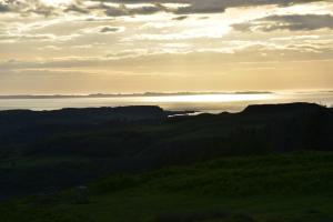a sunset over a body of water with the sun setting at Killoran House in Dervaig