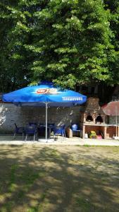 einen blauen Regenschirm mit Stühlen sowie einem Tisch und Stühlen in der Unterkunft Casa Borcean in Sasca Montană