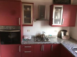 a kitchen with red cabinets and a stove top oven at Al Kawtar in Mohammedia