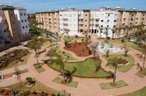 a park with palm trees in a city with buildings at Al Kawtar in Mohammedia