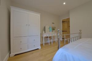 a bedroom with a large white cabinet and a table at Pippin Heath House B&B in Holt