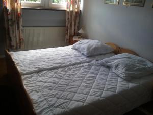 Una cama con sábanas blancas y almohadas en un dormitorio en Gudrun Waegner, en Welcherath