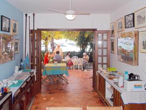 eine Küche mit Leuten, die an einem Tisch in einem Zimmer sitzen in der Unterkunft Pousada Manaca in Abraão