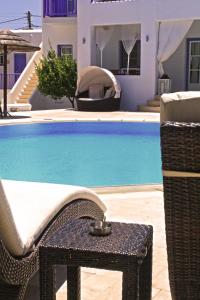 a wicker chair and a table next to a pool at Hotel Anatolia in Ano Mera