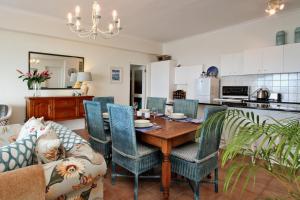 a kitchen and living room with a wooden table and chairs at Avian Leisure in Simonʼs Town