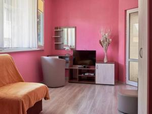 a living room with pink walls and a television at АПАРТАМЕНТ ЗА ГОСТИ "Момчил'' in Sofia