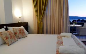 a bedroom with a white bed and a chair and a window at Ampoulos Rooms & Apartments in Kedro