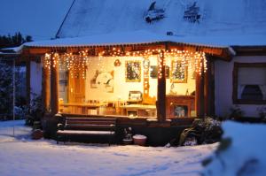una casa cubierta de luces de Navidad en la nieve en Apart Samay Hue Bungalows en Dina Huapi