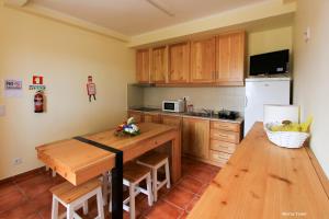 a kitchen with a wooden table and a refrigerator at Quinta Do Norte in Capelas
