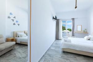 Cette chambre blanche comprend 2 lits et un miroir. dans l'établissement Memories Beach Hotel, à Monolithos
