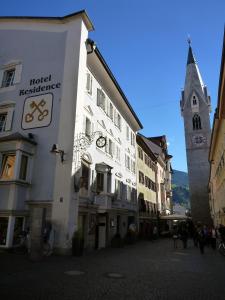 a group of buildings on a street with a clock tower at Residence Chiavi D'Oro - Goldener Schlüssel in Bressanone