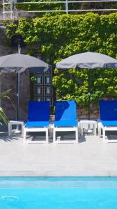 - deux chaises bleues et des parasols à côté de la piscine dans l'établissement Sole e Mare, à Santa-Maria-Poggio