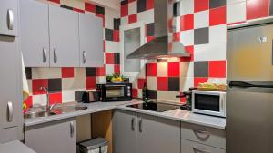 a kitchen with white cabinets and red and white checkered wall at Los Caňos II - Parking opcional in Jaén