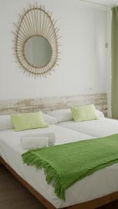 a bedroom with a white bed with a green blanket on it at Aparthotel Fleming 50 - Adults Only in San Antonio