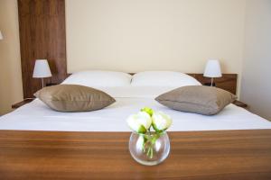 a bed with two pillows and a vase of flowers on a table at Villa Rooms Mediteran in Borovići