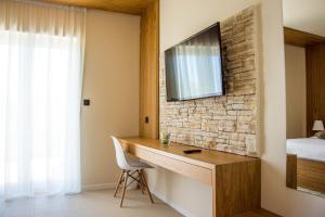 a bedroom with a desk with a television on a brick wall at Villa Rooms Mediteran in Borovići