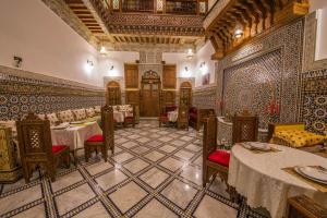 - un restaurant avec des tables et des chaises dans une salle dans l'établissement Riad Ouliya, à Fès