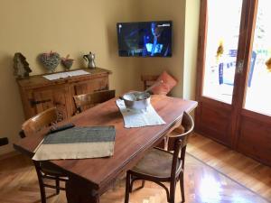 een houten eettafel met stoelen en een televisie bij Da Duccio e Maria in Acceglio