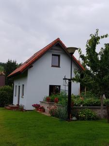 a white house with a red roof in a yard at Domek Kruklanki in Kruklanki