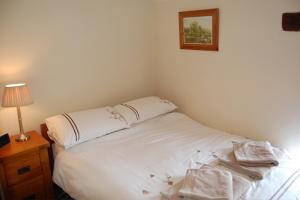 a bedroom with a white bed with towels on it at May Cottage in Tideswell