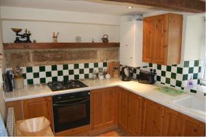 a kitchen with wooden cabinets and a stove top oven at May Cottage in Tideswell