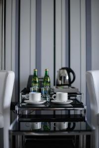 una mesa con botellas verdes y tazas. en Hotel Grafit en Kielce