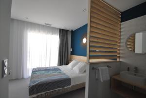 a bedroom with a bed and a sink and a mirror at Hôtel Café Miramar in Le Grau-du-Roi