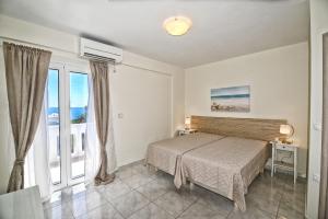 a bedroom with a bed and a large window at Peskesi Ikaria in Agios Kirykos