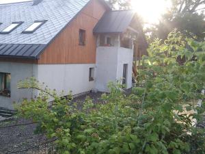 a house with a wooden roof and some bushes at Apartmány Kuřátko in Benecko