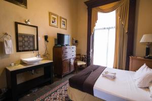 um quarto com uma cama, um lavatório e um espelho em El Gran Hotel em Mérida