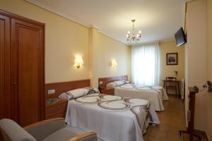 a hotel room with three beds with white sheets at Hotel Pantón in Vigo