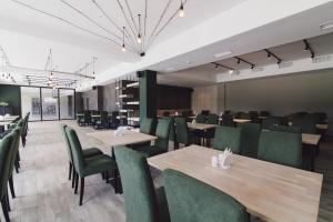 ウージュホロドにあるZinedine Sport-Hotelの木製テーブルと緑の椅子が備わるレストラン