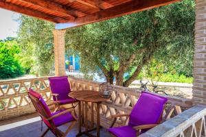 porche con sillas moradas y mesa de madera en Porto Gerakas Villas, en Vasilikos