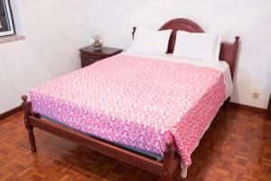 1 dormitorio con 1 cama con edredón rosa en Home Pico - Casa dos Cedros (Alojamento local) en Criação Velha