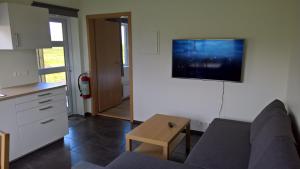 a living room with a couch and a tv on the wall at Sefdalur Studio Apartment in Höfn