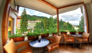a balcony with tables and chairs and a large window at Plaza Family Hotel in Smolyan