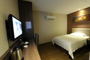 a hotel room with a bed and a flat screen tv at The Imperial Hotel in Kluang