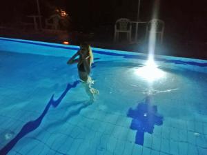 een vrouw die 's nachts in een zwembad staat bij Violetta Hotel in Amoudara Herakliou