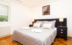 een witte slaapkamer met een groot bed en 2 handdoeken bij Casa Ana in Zadar